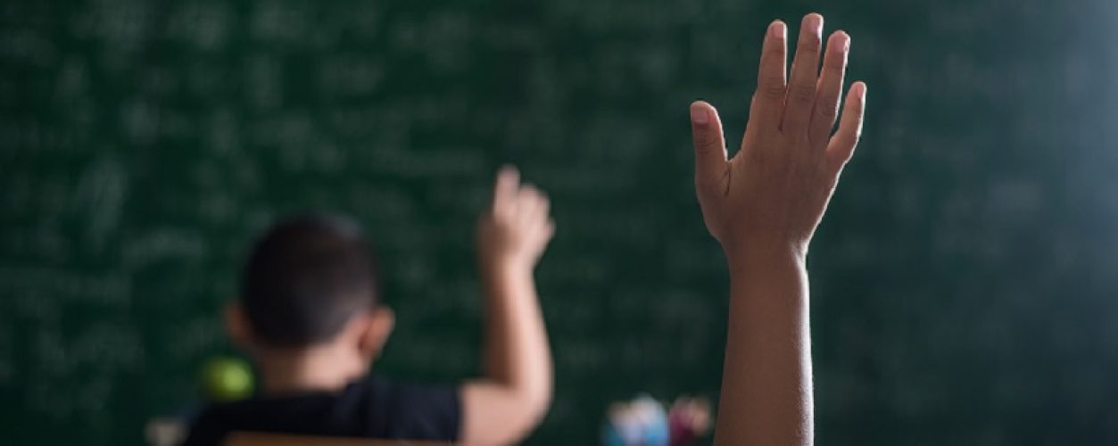 kid raising his hand in classroom